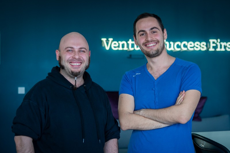 Aiger and Emanuel at the Project A office. Behind them is a neon sign with one of the company values: Venture Success First